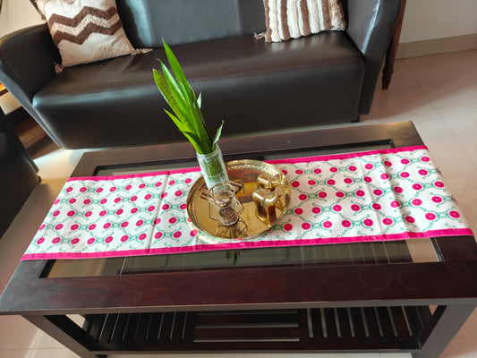 Decorative table setting with a polka dot runner, gold tray, and plant on a coffee table.