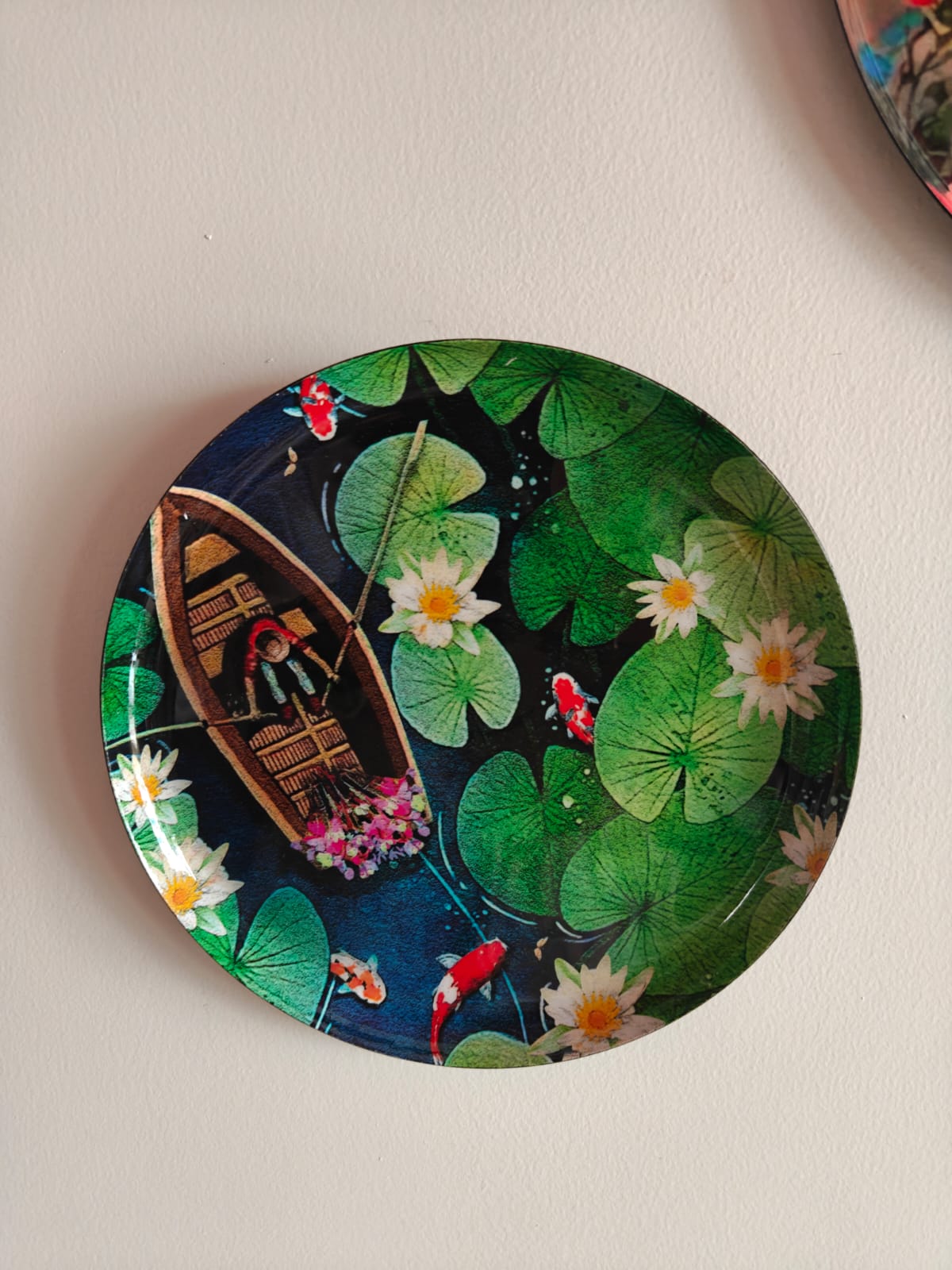 Decorative plate with a design of a boat, flowers, and fish on a dark background