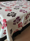 Floral patterned tablecloth with red, black, and purple flowers on a white background.