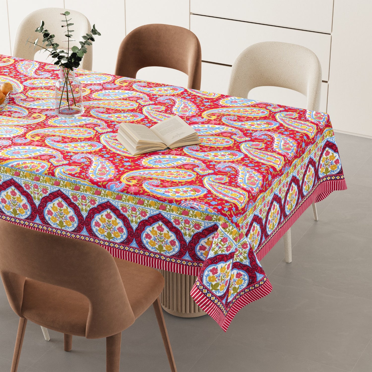 Colorful paisley-patterned tablecloth on a dining table with chairs.