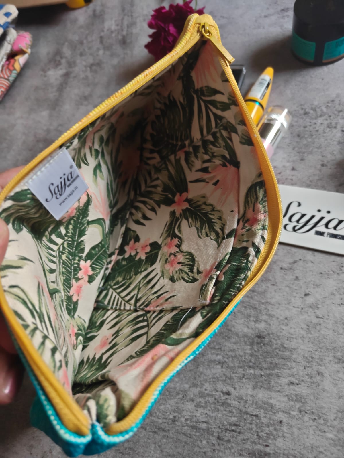 Floral-patterned pouch with yellow trim on a gray surface