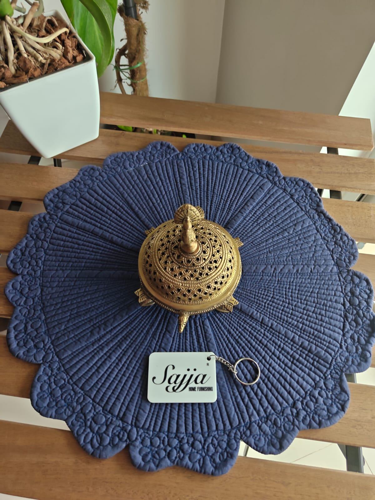Blue textured placemat with a gold decorative item and 'Sajja' tag on a wooden surface.